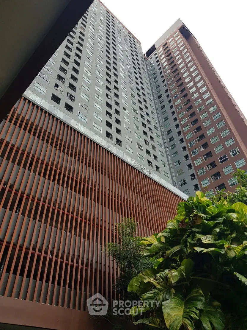 Modern high-rise building with lush greenery and unique architectural design.
