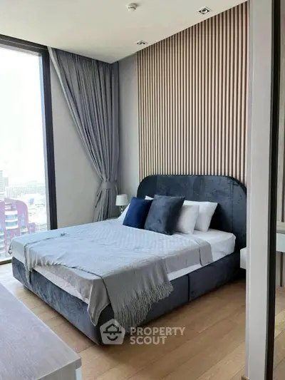 Modern bedroom with stylish decor and large window offering city views.