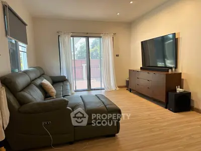 Spacious living room with modern leather sofa and large TV, perfect for relaxation and entertainment.