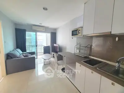 Modern open-layout living room with kitchen, featuring sleek furniture and balcony access.