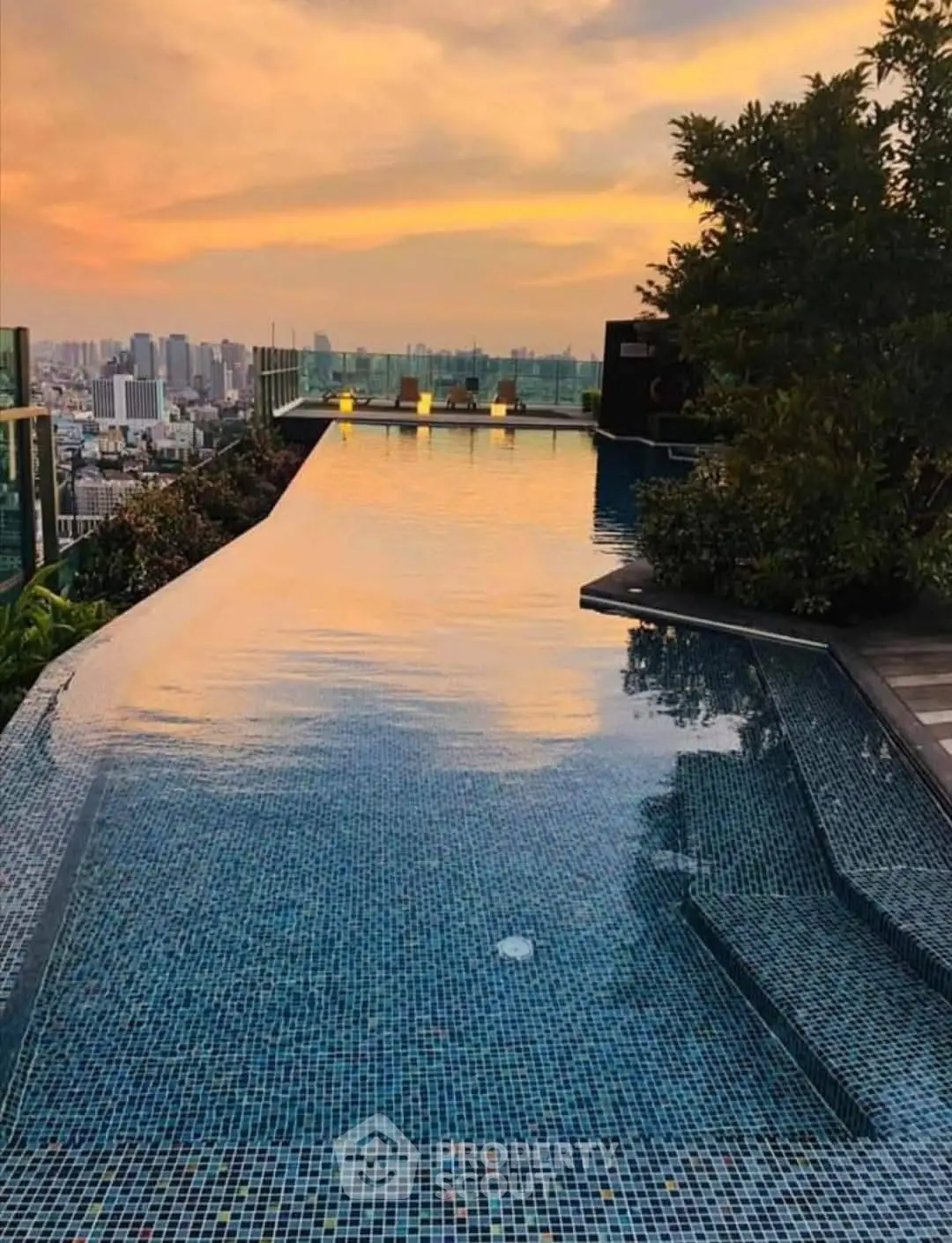Stunning rooftop infinity pool with breathtaking city skyline view at sunset.
