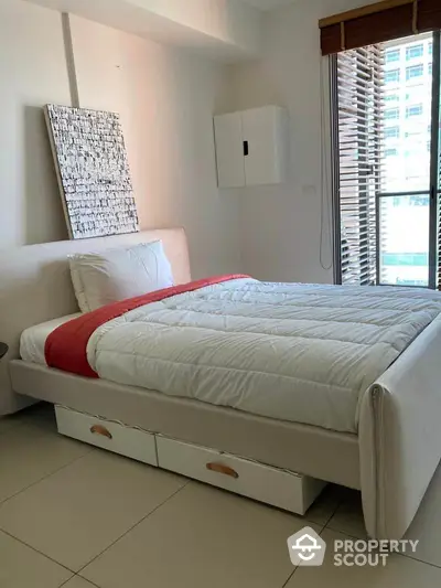 Bright and airy bedroom with a large comfortable bed, storage drawers, and modern decor, perfect for restful nights in a city apartment.