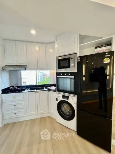Modern kitchen with sleek appliances and elegant cabinetry in a bright corner unit.