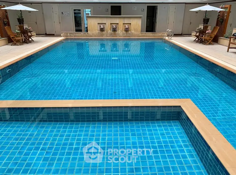 Luxurious swimming pool with elegant design and poolside seating area in a premium real estate property.