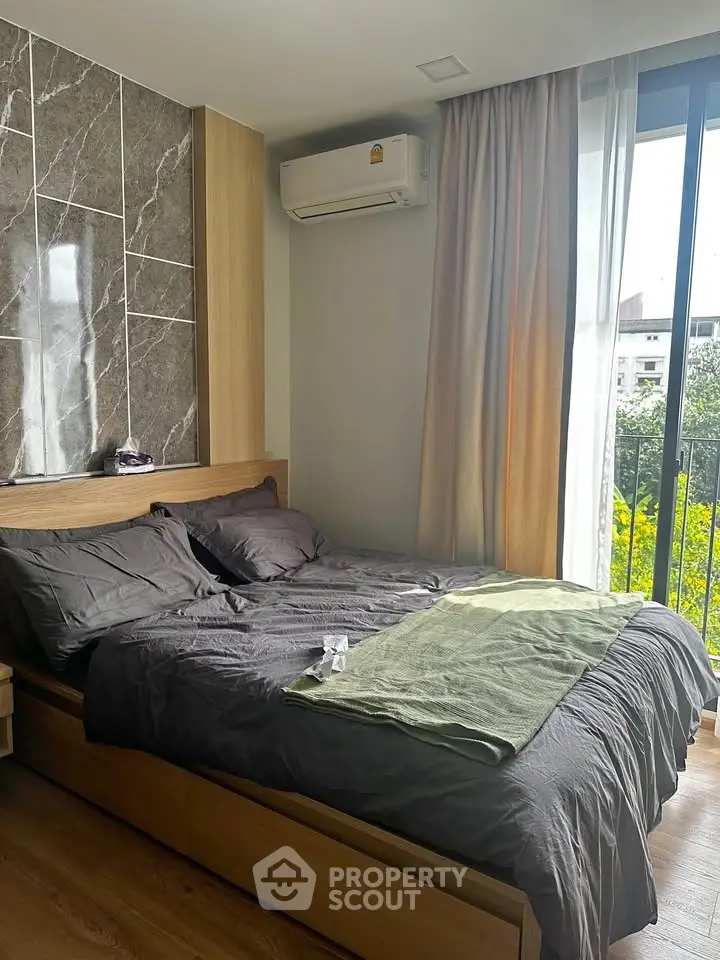 Modern bedroom with stylish decor and large window offering natural light and garden view.