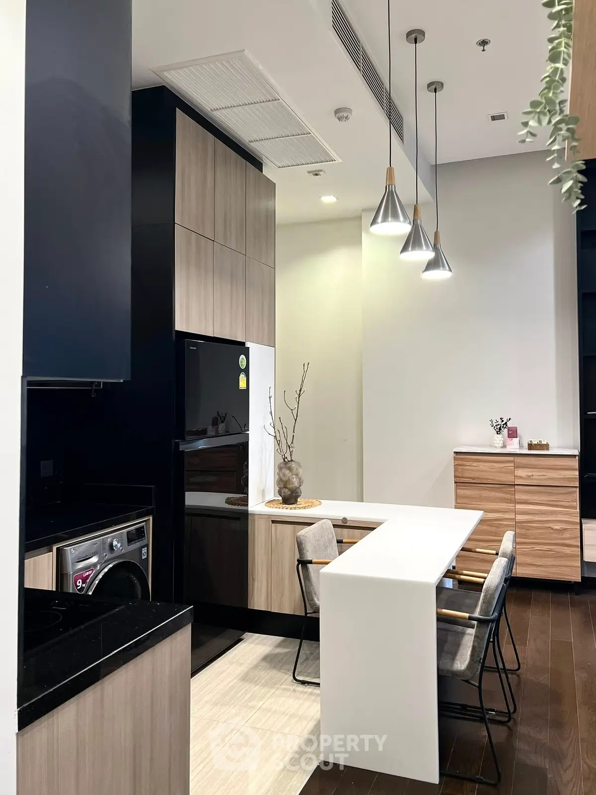 Modern kitchen with sleek design, featuring a washing machine and stylish pendant lights.