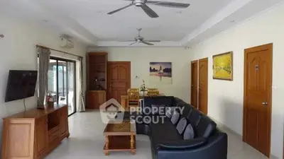 Spacious living room with modern decor and large black leather sofa