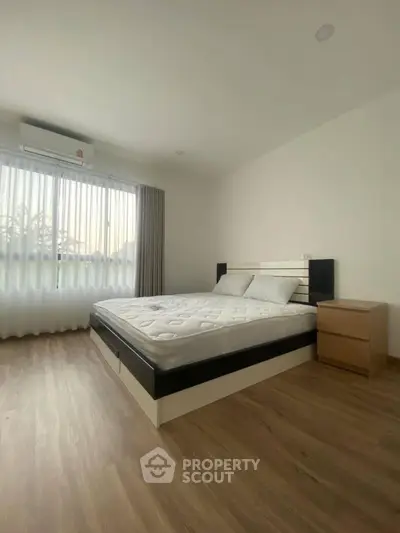 Spacious bedroom with modern design and large window for natural light.