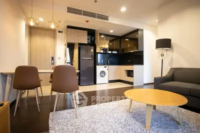 Modern open-plan living room with kitchen, featuring stylish furniture and appliances.