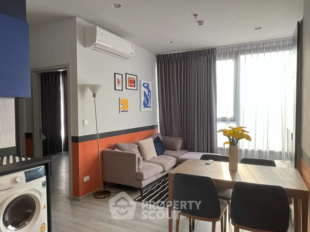 Modern living room with cozy sofa, dining table, and washing machine in stylish apartment.