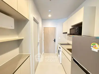 Modern kitchen with sleek cabinetry, washing machine, and stainless steel fridge in a compact layout.
