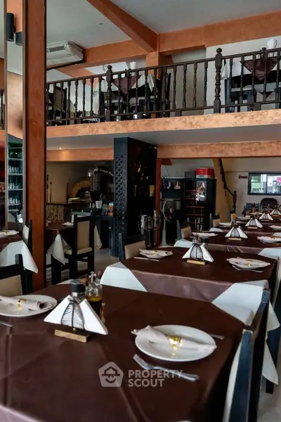 Charming restaurant interior with elegant table settings and mezzanine seating area.