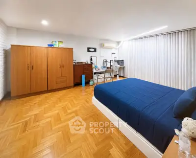 Spacious bedroom with wooden flooring and modern furnishings