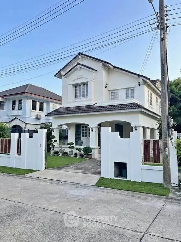 Charming two-story white house with a manicured lawn and modern fence in a suburban neighborhood.