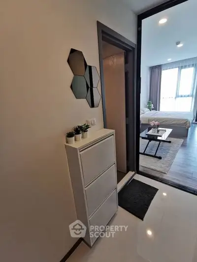 Modern apartment entrance with stylish decor and view into cozy bedroom