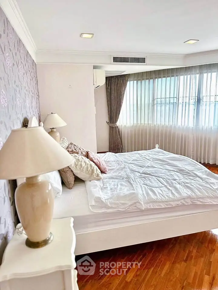 Spacious bedroom with elegant decor and large windows for natural light.
