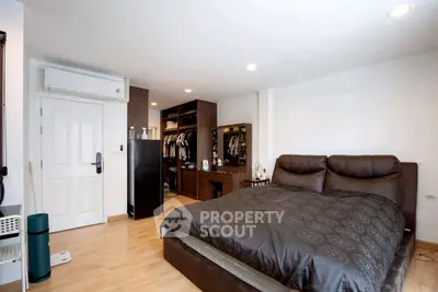 Spacious bedroom with elegant decor and walk-in closet, featuring modern lighting and hardwood flooring.