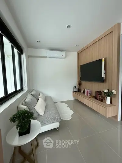 Modern living room with sleek design, featuring a wall-mounted TV, cozy sofa, and stylish decor.