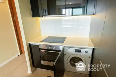 Compact modern kitchen with built-in appliances and ample storage space, showcasing a sleek design ideal for urban living.