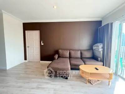 Spacious living room with modern brown sofa and wooden coffee table, featuring a large window with city view.