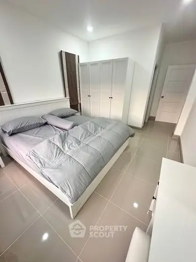 Spacious modern bedroom with sleek tile flooring and ample closet space.