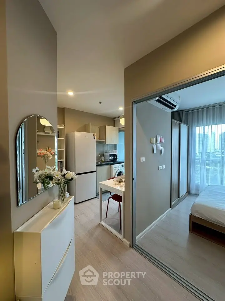 Modern apartment interior with kitchen and bedroom, featuring sleek design and natural light.