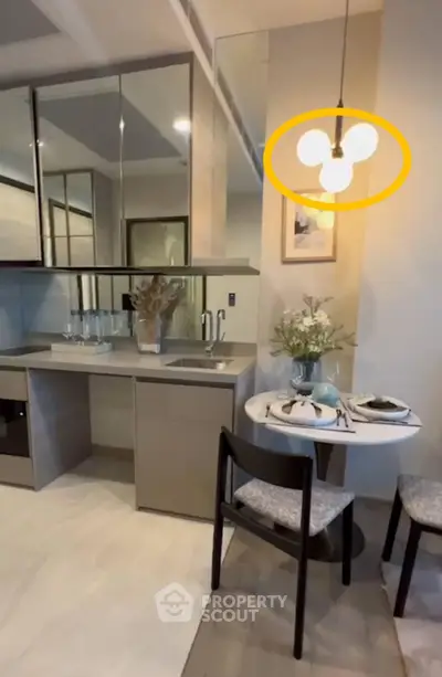 Modern kitchen with sleek cabinetry and cozy dining area, featuring stylish lighting and elegant decor.