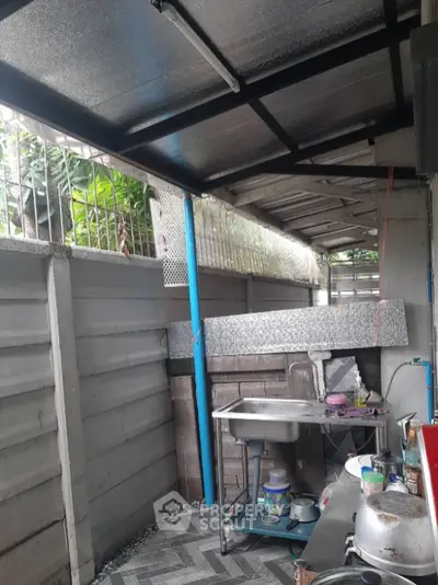 Outdoor kitchen area with metal roof and sink, featuring a compact layout and functional design.