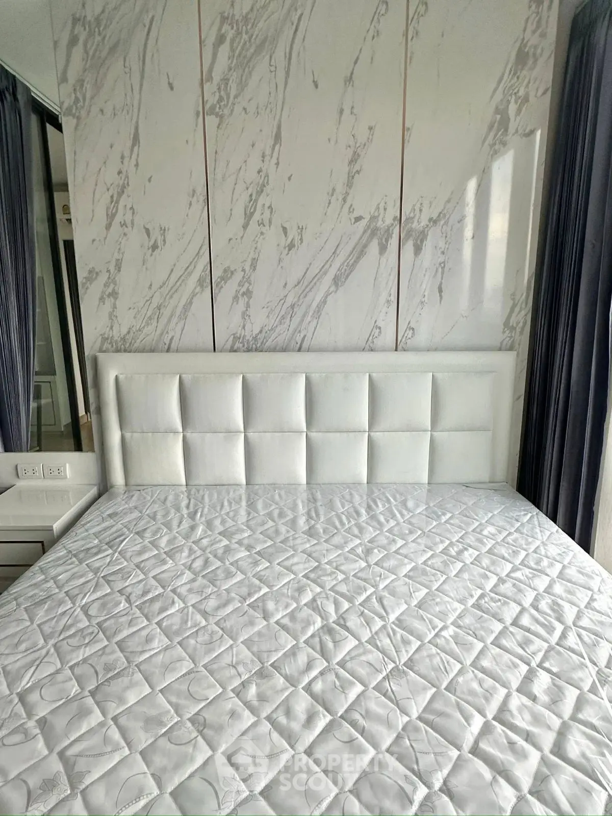 Luxurious bedroom with elegant marble accent wall and plush white headboard