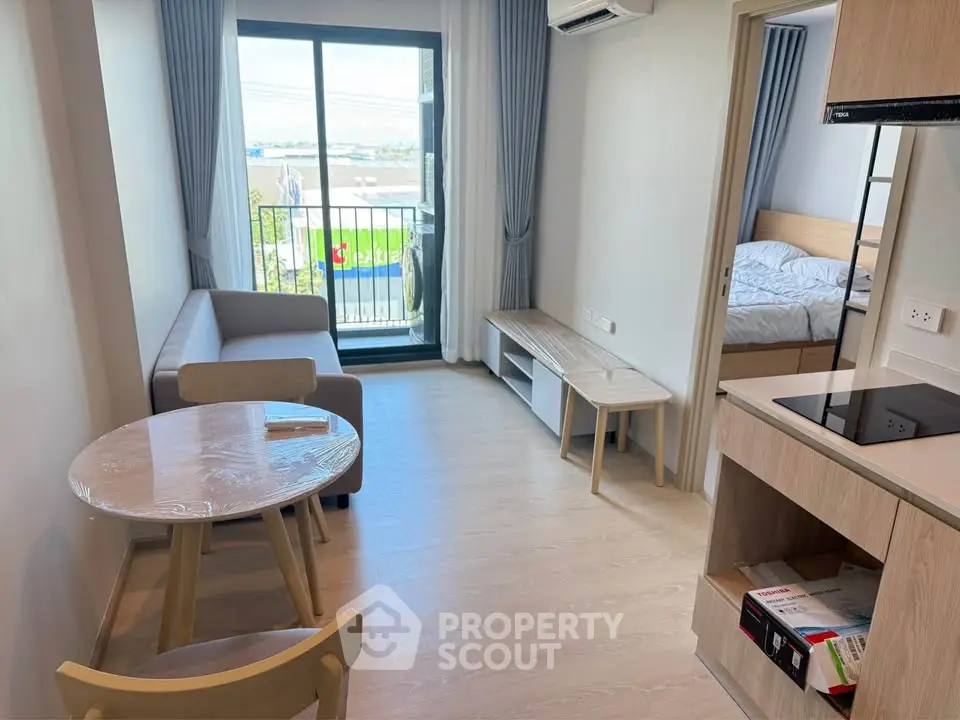 Modern apartment interior with open layout, featuring a cozy living area, compact kitchen, and balcony view.