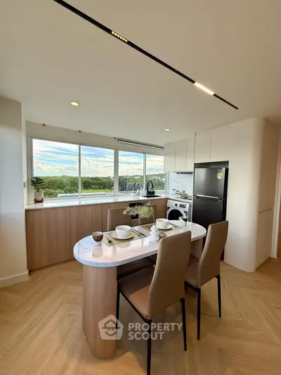 Modern kitchen with open layout and scenic view, featuring sleek appliances and elegant dining area.