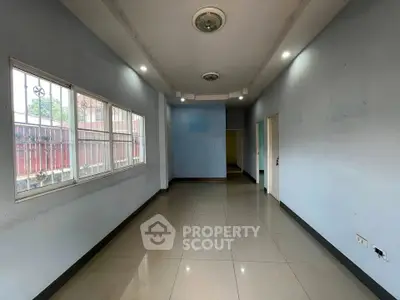 Spacious empty room with tiled flooring and large windows, ideal for customization.
