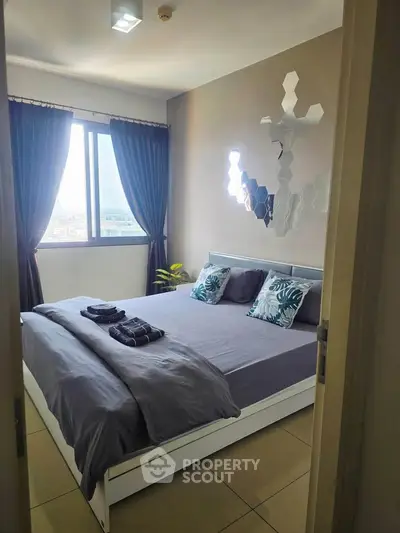 Modern bedroom with stylish decor and large window offering city views.