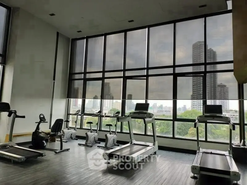 Spacious gym with modern equipment and city view, perfect for fitness enthusiasts.