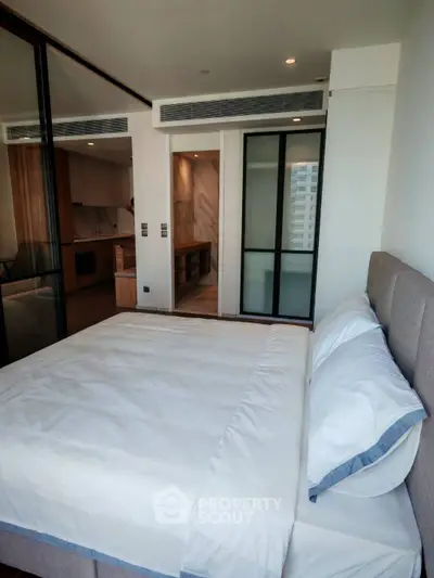 Modern bedroom with glass partition and cozy bedding in a stylish apartment