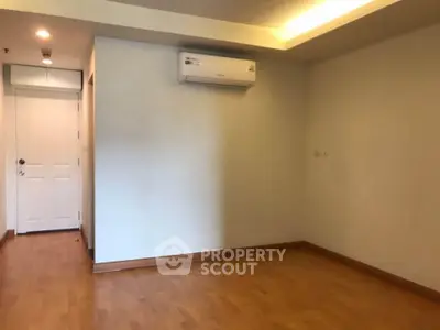 Spacious empty room with wooden flooring and air conditioning, ideal for customization.
