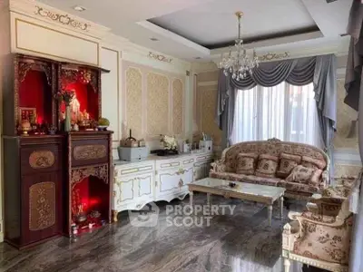 Luxurious living room with elegant furniture and chandelier, featuring ornate decor and large window.