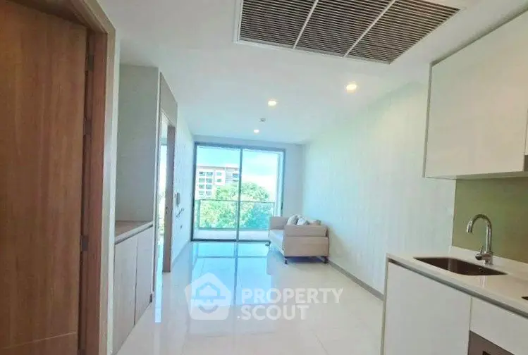 Bright modern living room with large windows and sleek kitchen area.