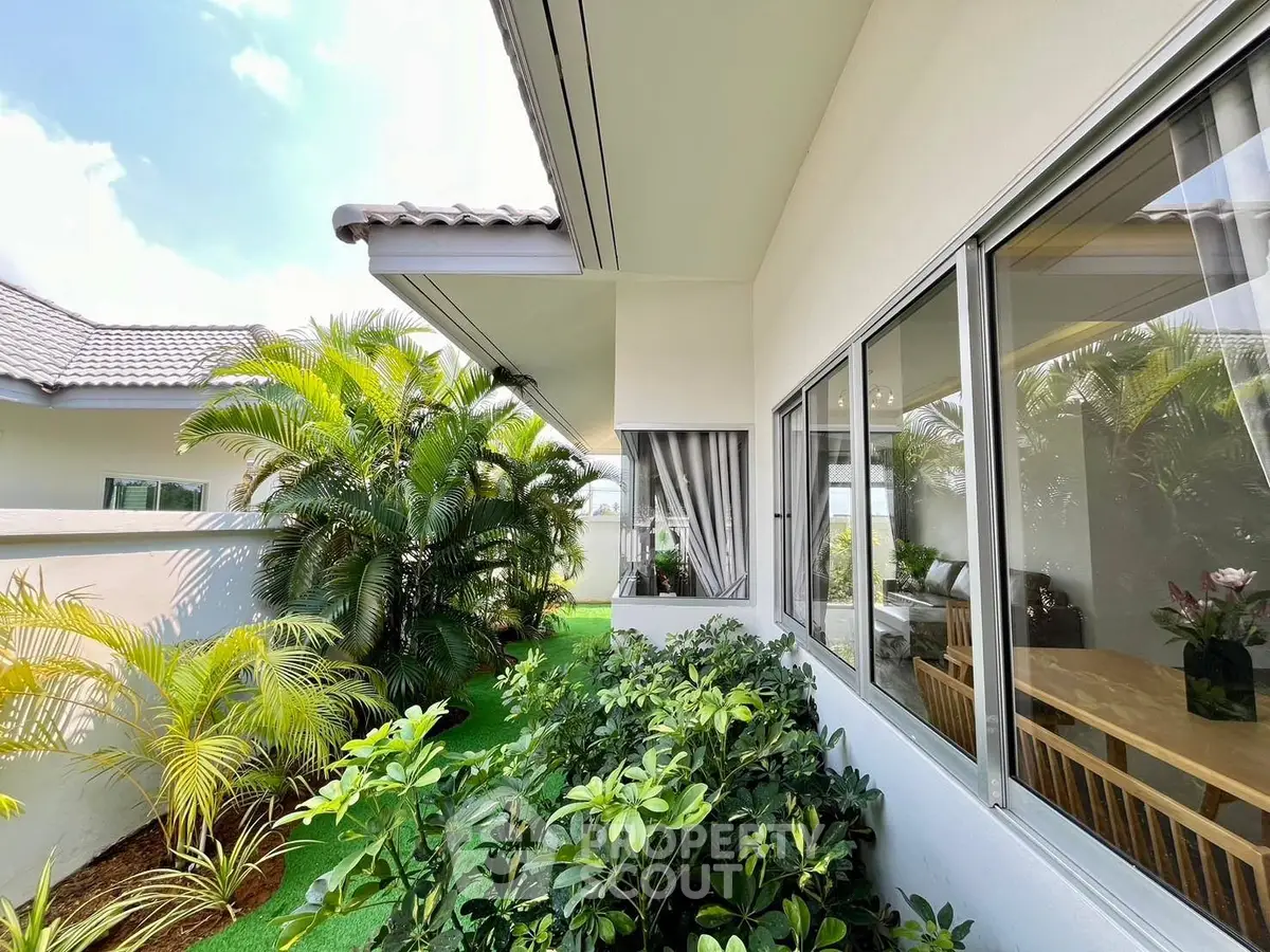 Charming exterior view of modern home with lush garden and large windows, perfect for natural light lovers.