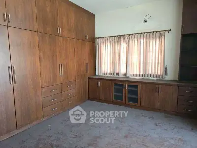 Spacious bedroom with ample wooden storage and natural light.