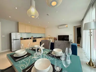 Modern open-plan living room with stylish kitchen and dining area, featuring elegant decor and natural light.
