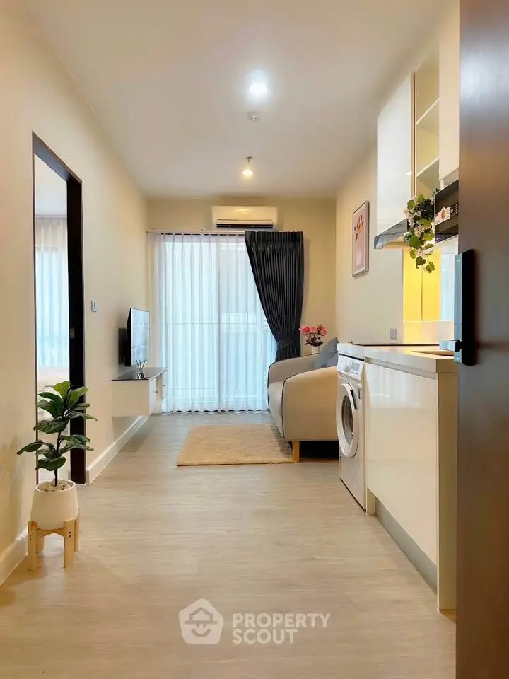 Modern living room with washing machine and cozy decor in open layout apartment.