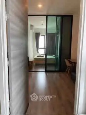 Modern apartment entrance with glass partition leading to a cozy bedroom.