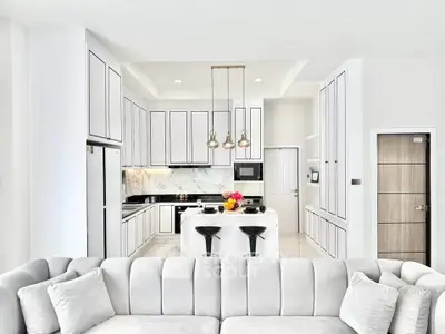 Luxurious modern kitchen with sleek white cabinetry and elegant island seating.