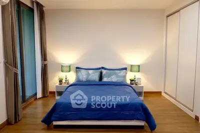 Spacious bedroom with modern decor and large windows for natural light.