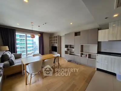Modern open-plan living room with dining area and kitchen in a high-rise apartment with city view.