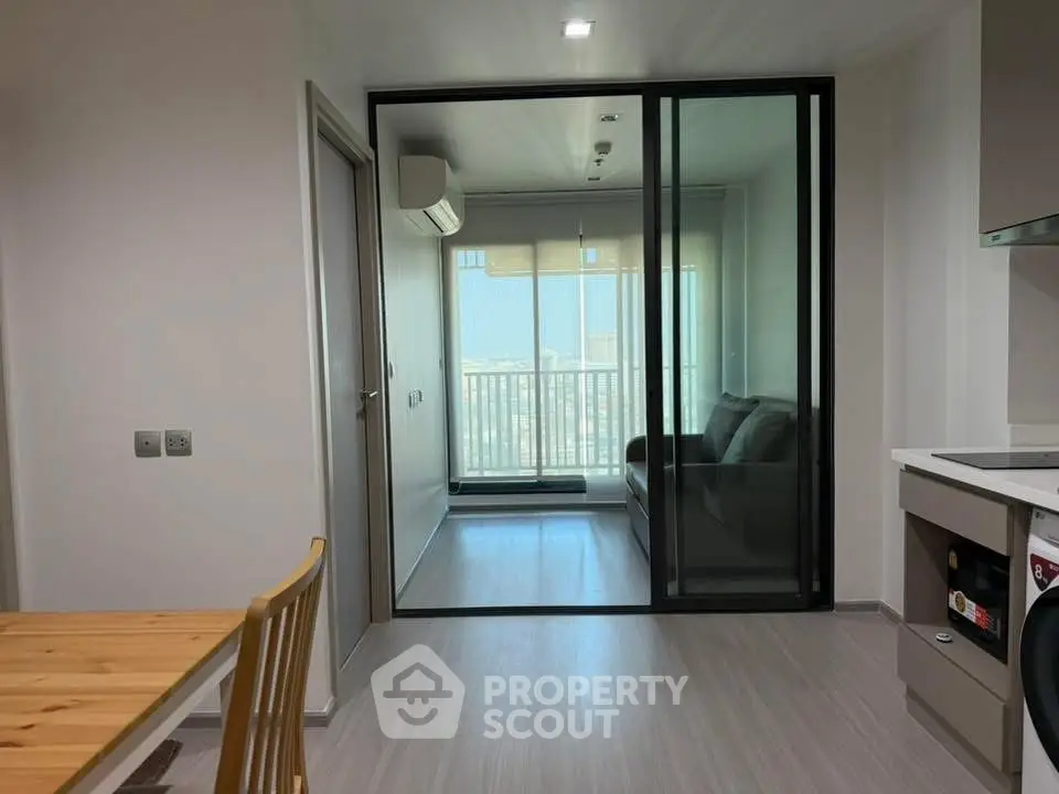 Modern apartment interior with glass sliding doors and city view balcony.