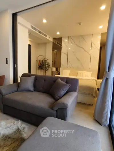 Modern open-plan living room with cozy sofa and elegant bedroom in luxury apartment.