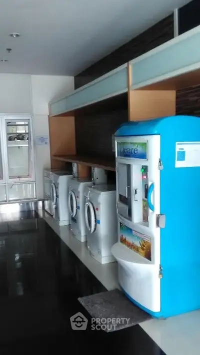 Modern laundry area with washing machines and vending machine in sleek apartment complex.