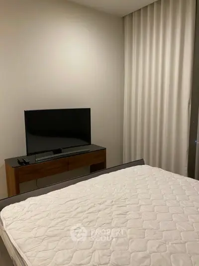 Modern bedroom with TV and minimalist decor, featuring a comfortable bed and sleek furniture.